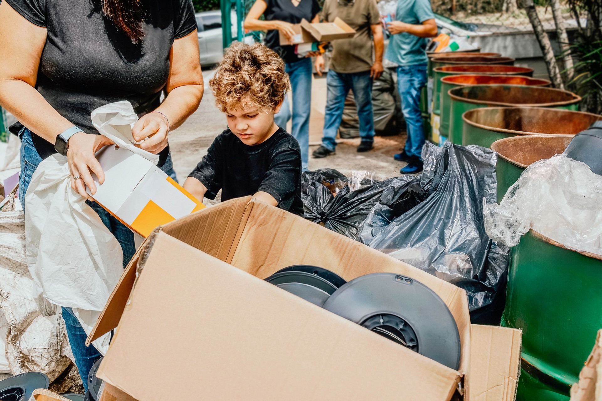 Volunteers and a child sorting plastic for recycling in community cleanup